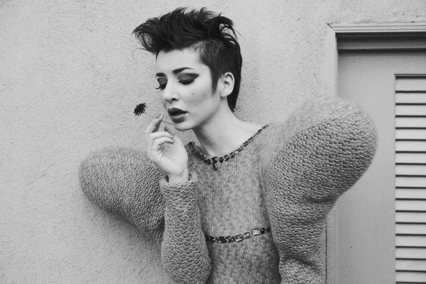 Black-and-white fashion portrait holding a flower