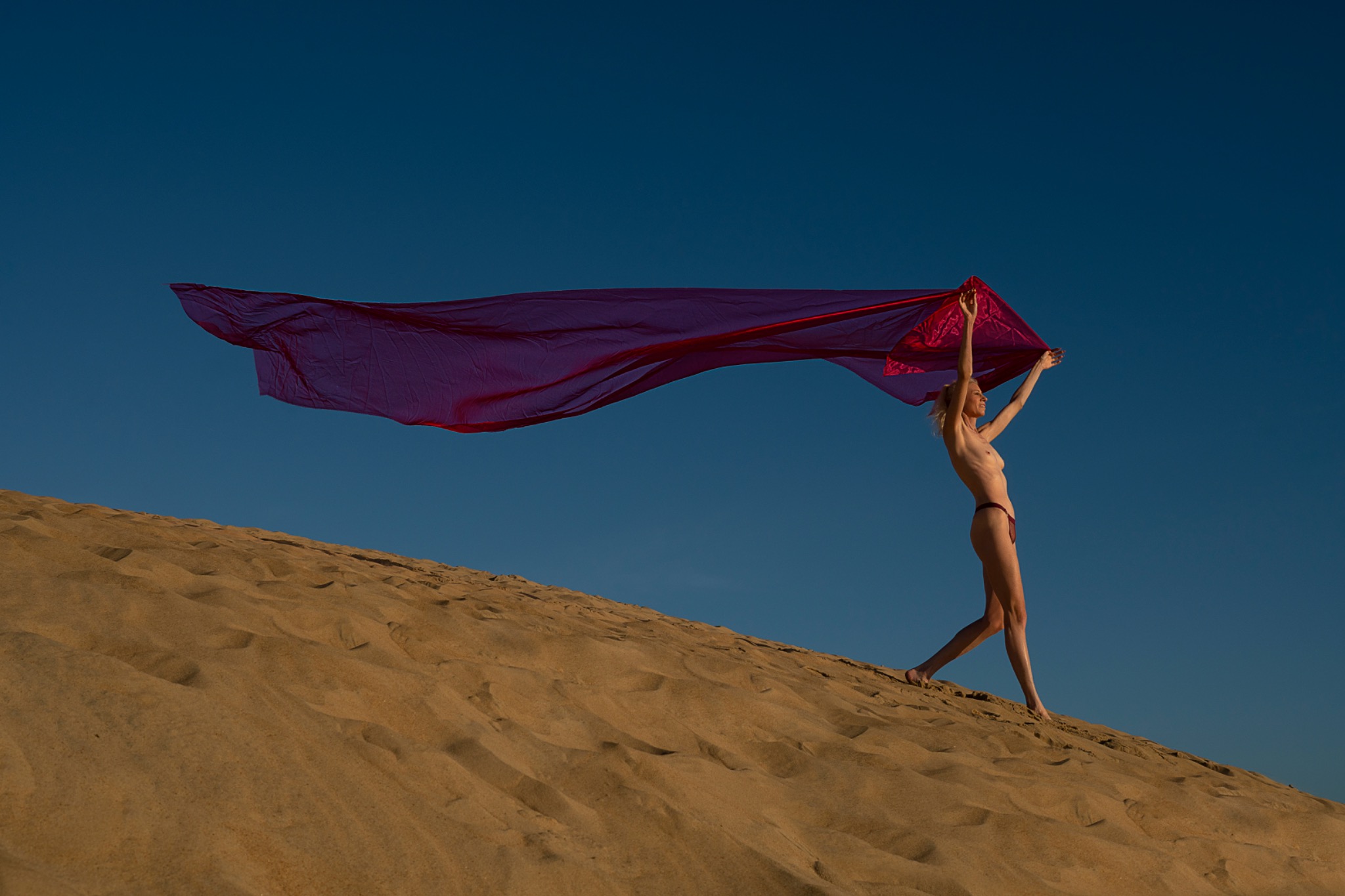 Fashion photograph with flowing red fabric on a sand dune by Jeff Linett