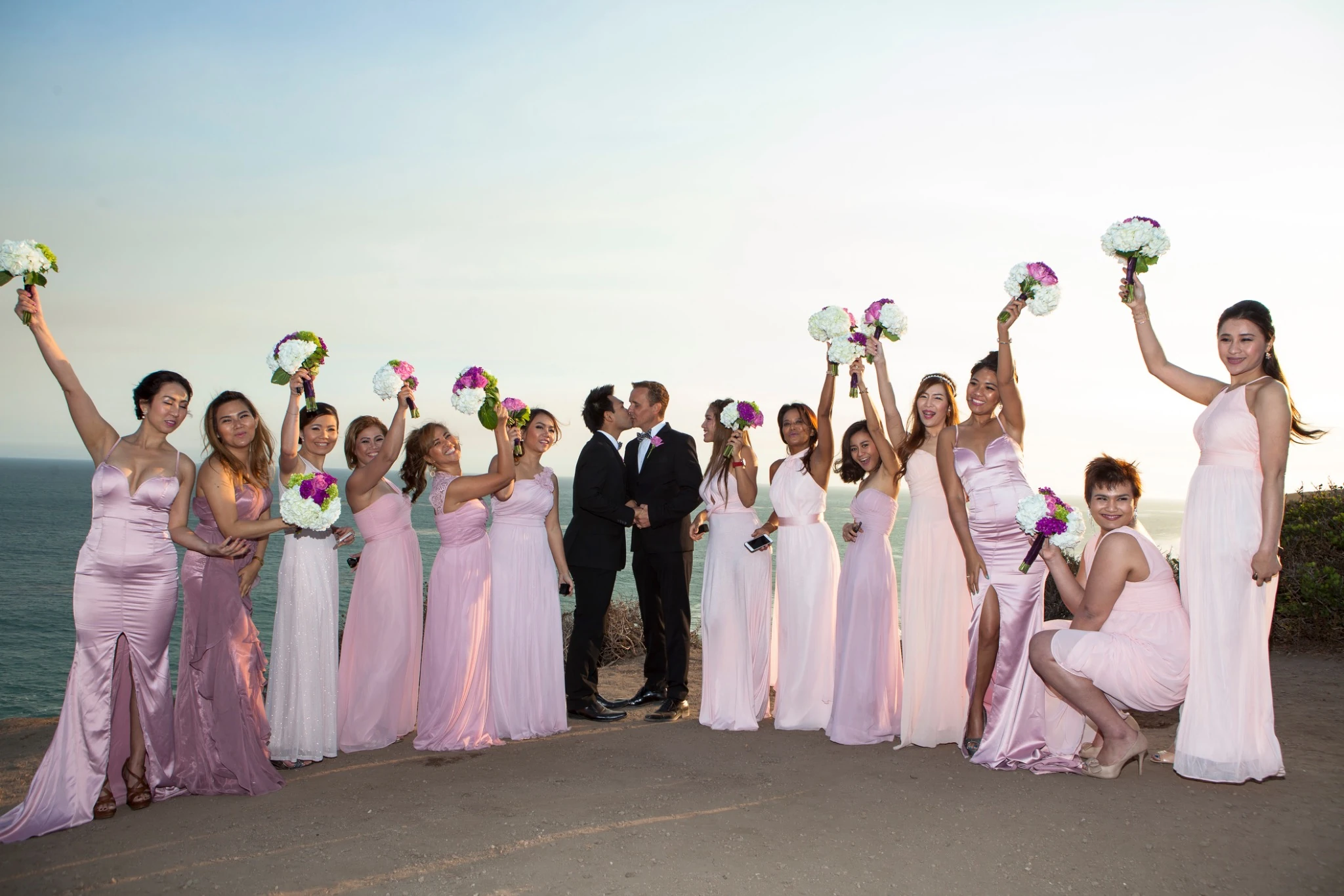 Wedding party celebrating by the sea by Jeff Linett
