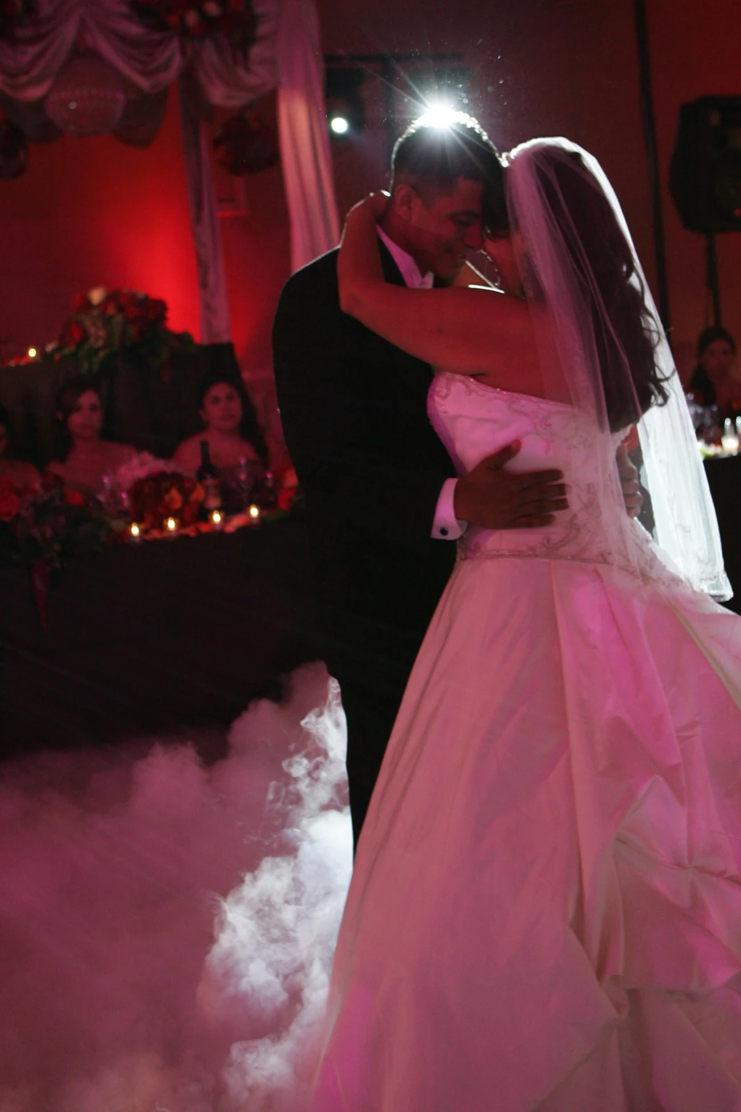 Newlyweds dancing in red reception light by Jeff Linett