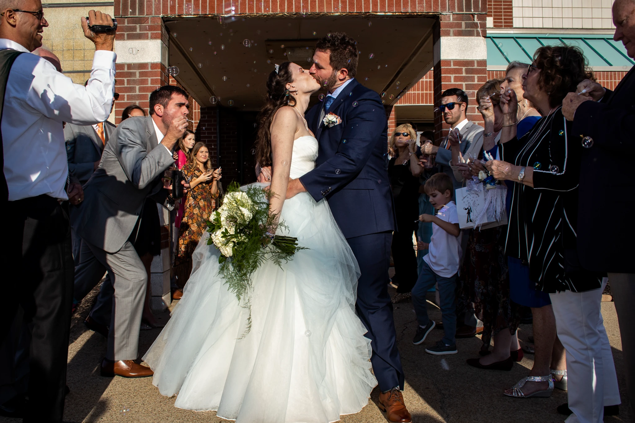 Newlyweds kissing beneath bubbles by Jeff Linett